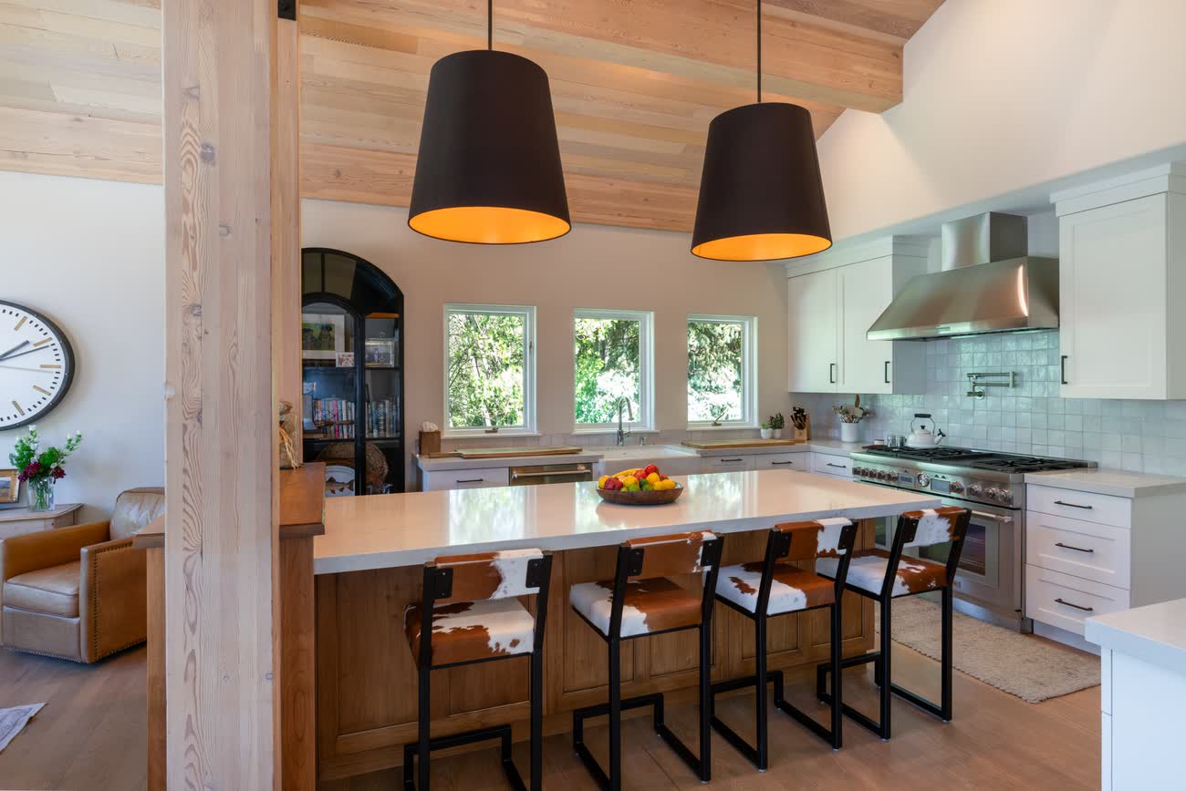 Kitchen with a long island, pendant lighting and range beneath a copper hood