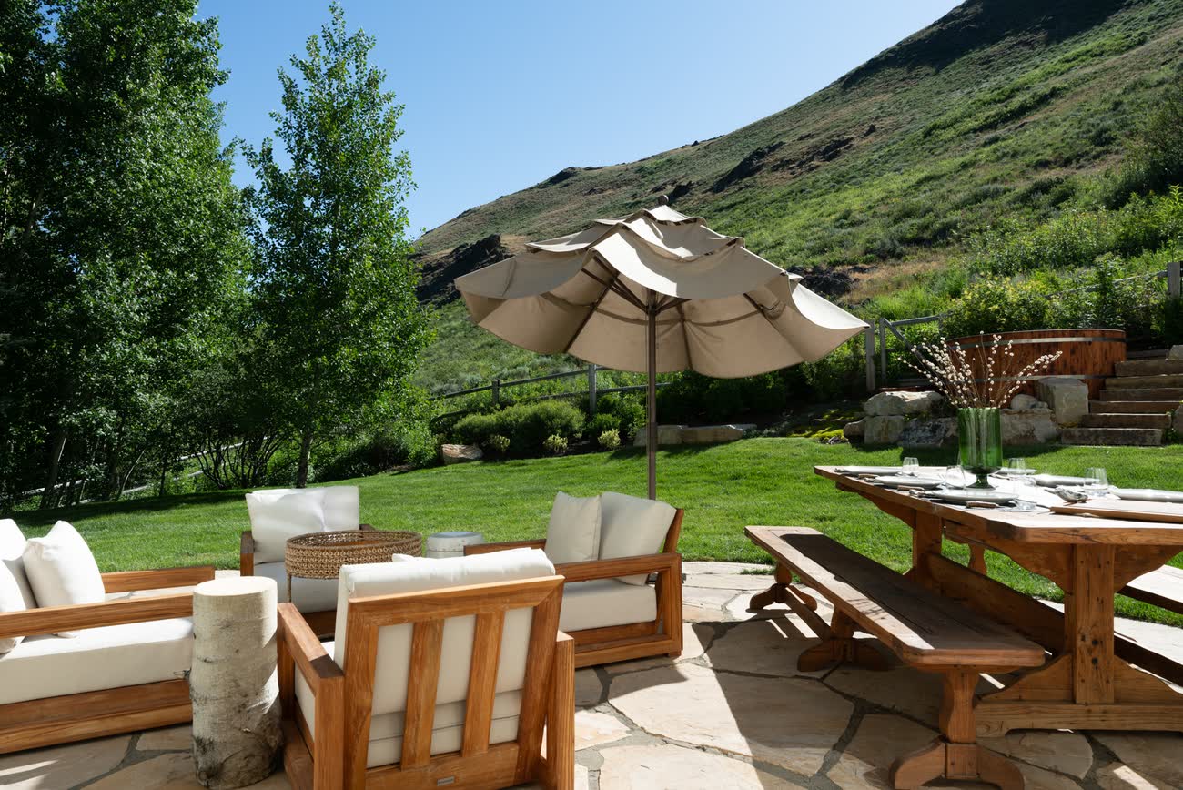 Terrace dining set beneath umbrellas with the foothills beyond