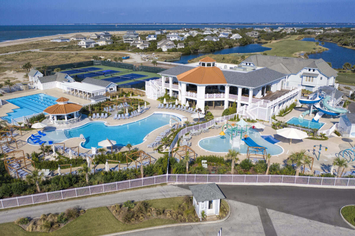 Aerial view of Bald Head Island Club aquatics center with water slides, pools, and Atlantic Ocean in the background