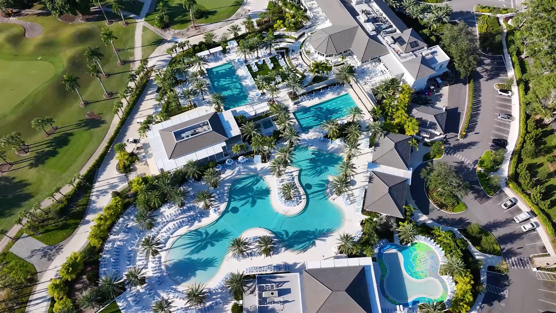 Aerial view of Boca West Country Club aquatics center showing five interconnected pools surrounded by palm trees and golf course