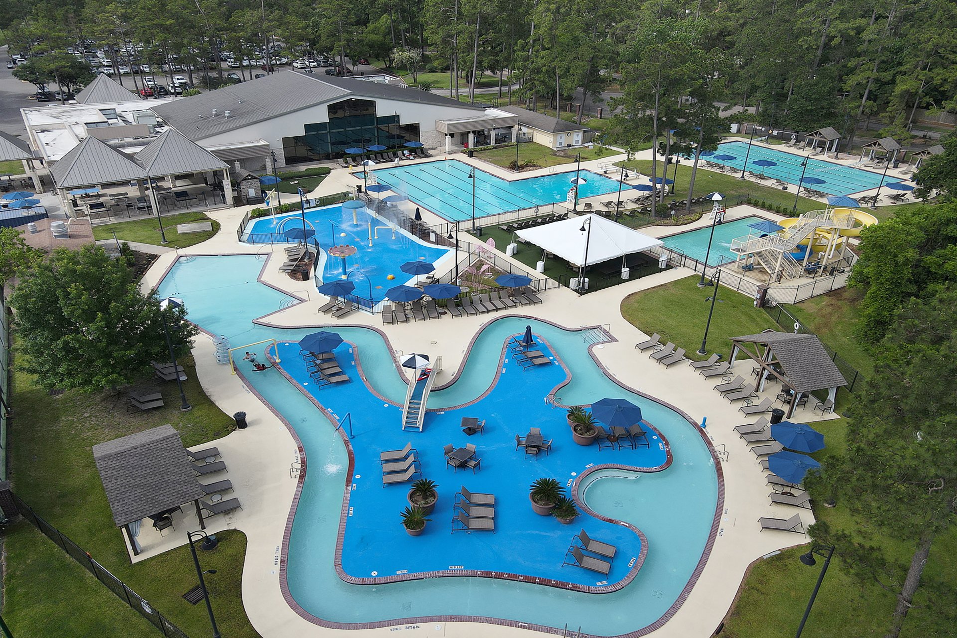 Aerial drone view of The Clubs of Kingwood water park showing lazy river, water slides, and multiple pool areas
