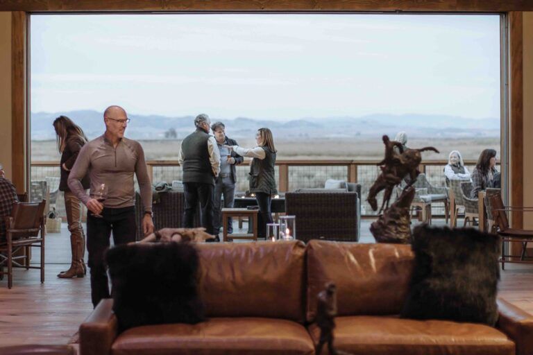 Members gathered in a club lounge overlooking open country at Wing and Barrel